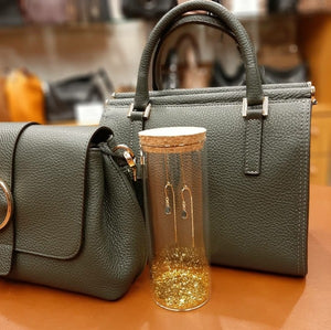 Oorbelletjes in een glazen koker met gouden glitters.